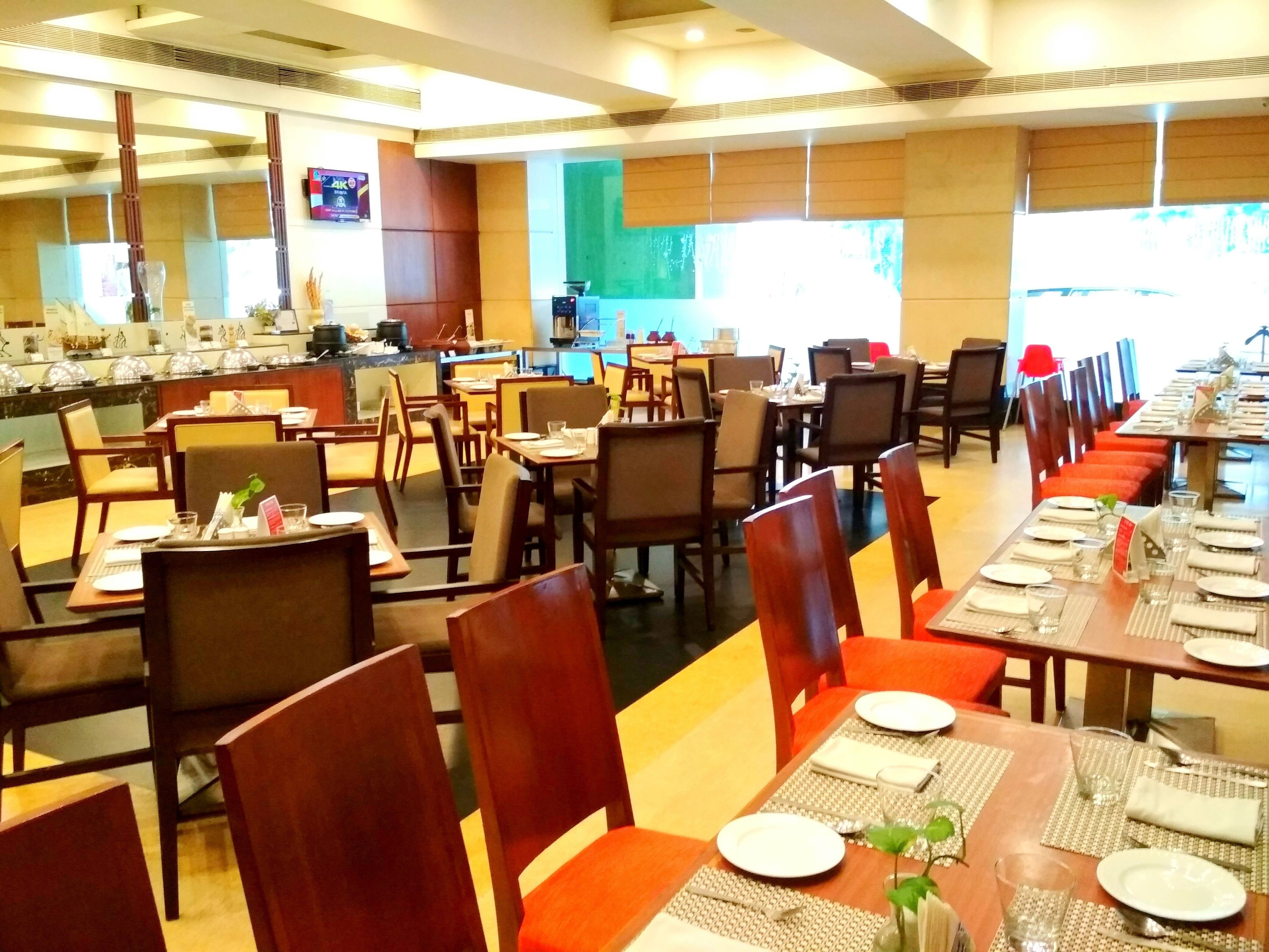 A restaurant with multiple dining tables and chairs, a buffet area, and a counter with food items.