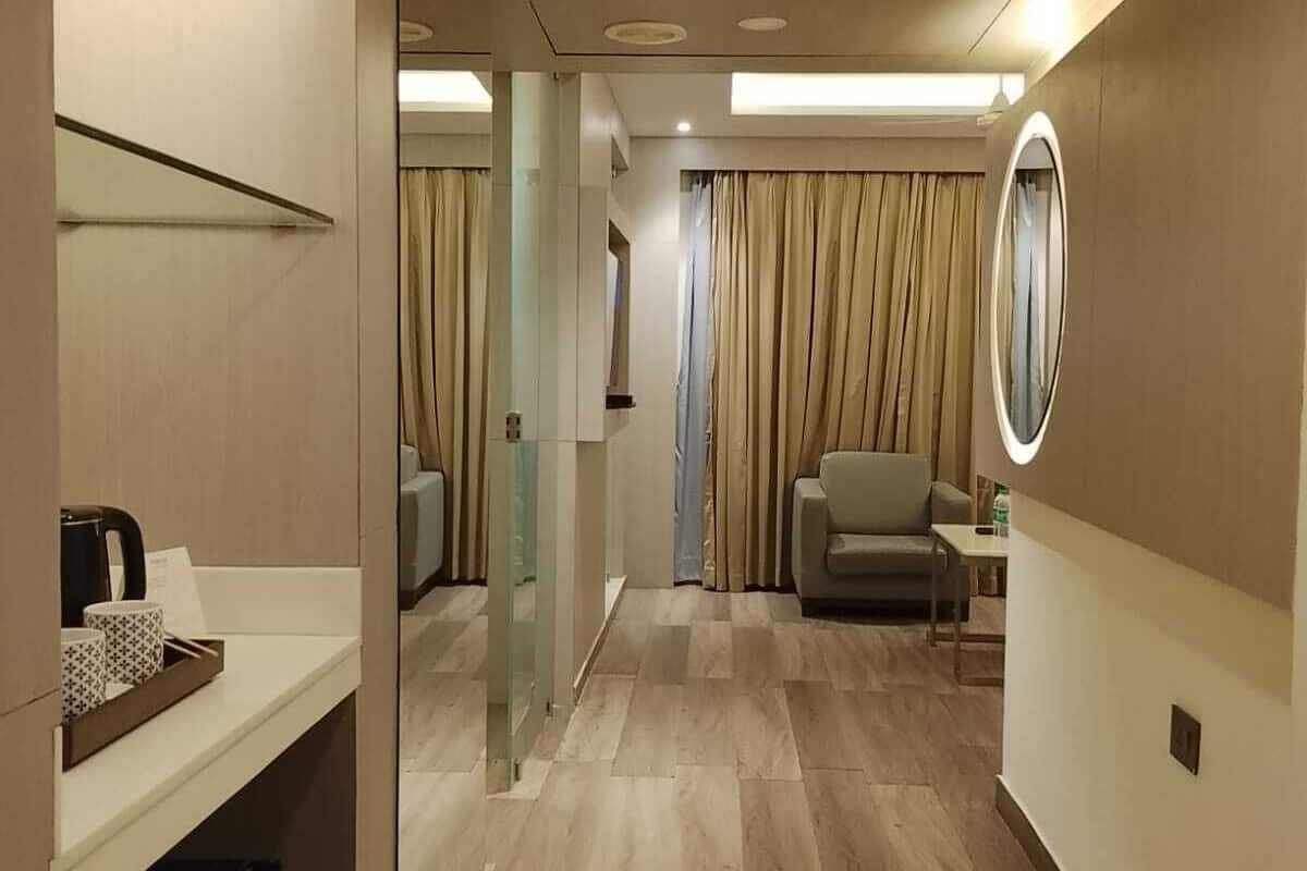 Habitación de hotel con baño, zona de estar y un espejo.