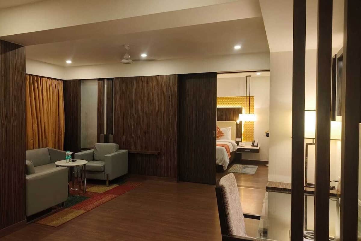 Una habitación de hotel moderna con zona de estar, cama y espacio de trabajo separado.