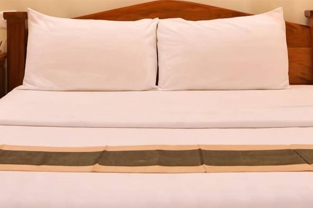 Ein Bett mit weißer Bettwäsche und einem braunen Kopfteil.