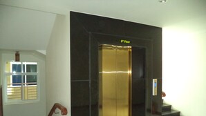 Un ascensor en el octavo piso con puerta de vidrio y barandilla.