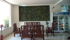 Una habitación con muebles de madera tradicionales, un gran elemento decorativo en la pared y un refrigerador lleno de bebidas.