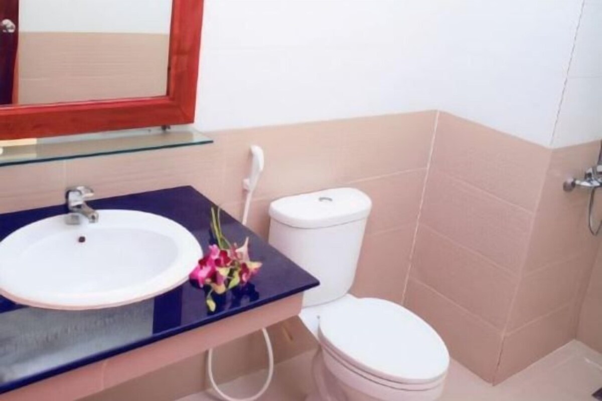 Un baño con un lavamanos blanco, un estante de vidrio encima, un inodoro blanco y un espejo con marco de madera.