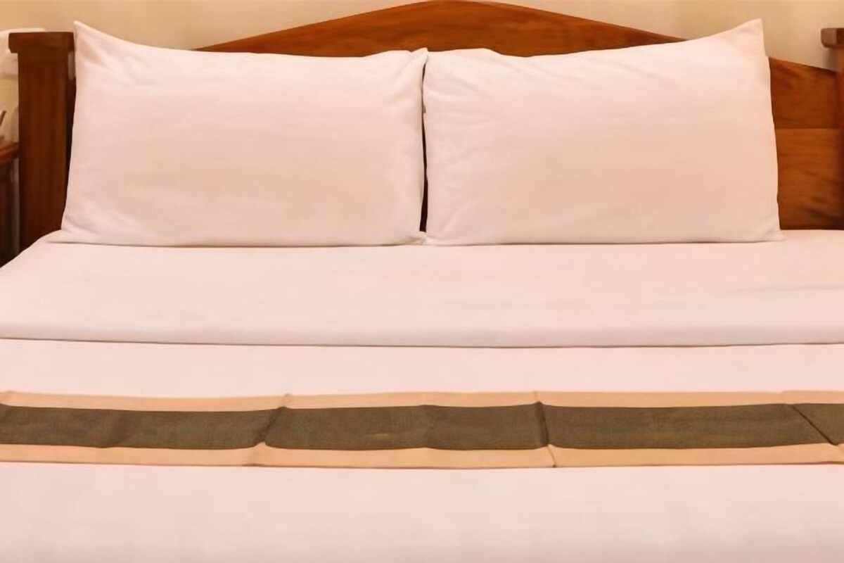 A bed with white bedding and a brown headboard.