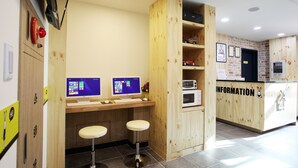 A reception area with wooden paneling, two computer monitors, a microwave, and a counter labeled "INFORMATION".