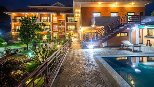 Un hotel con piscina, un jardín bien iluminado y una escalera que conduce a los pisos superiores.