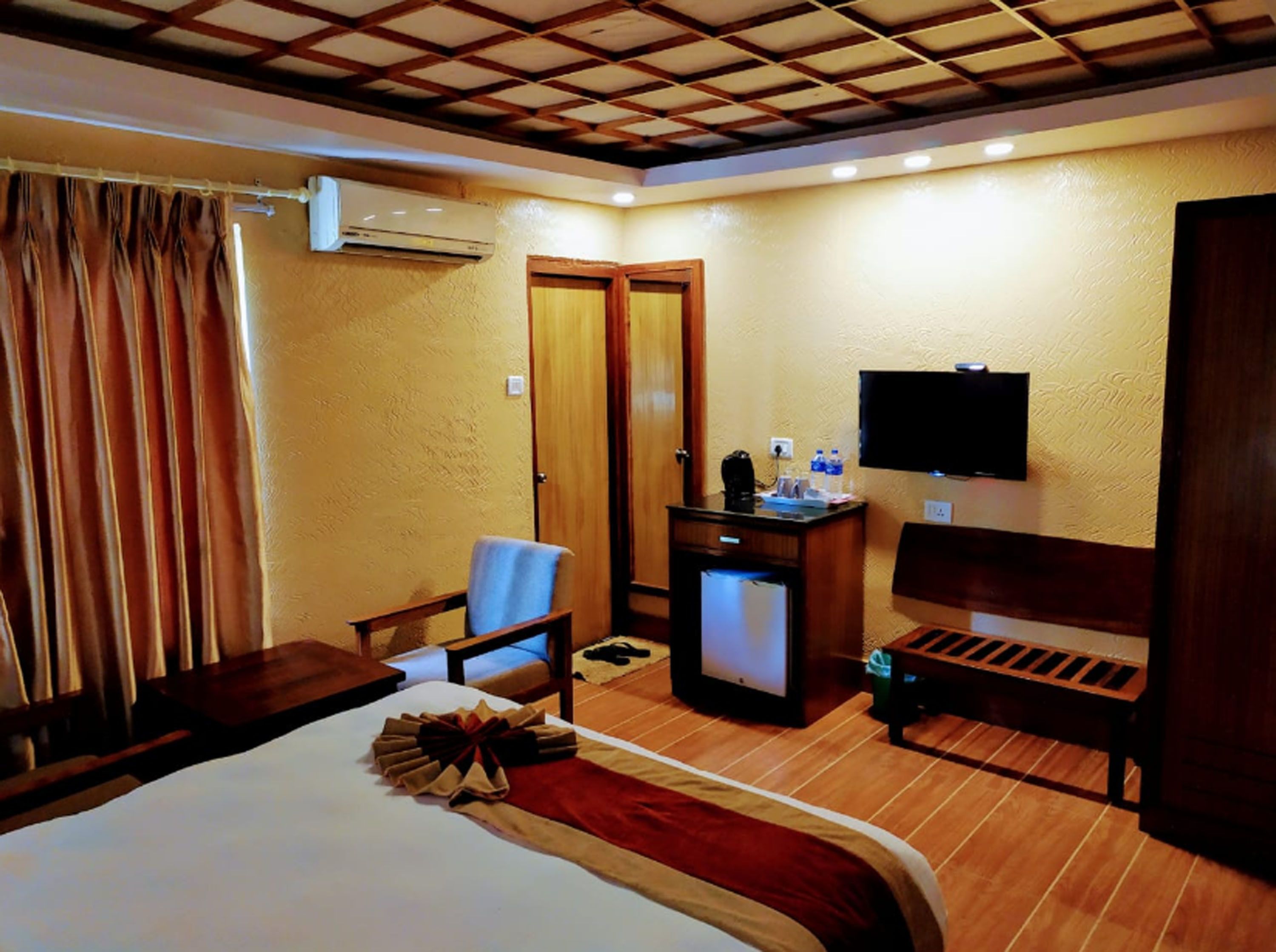 Una habitación de hotel con cama, escritorio, silla, televisor y minibar.