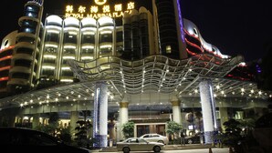 Ein Hotel mit modernem Design, gekennzeichnet durch einen markanten Eingangsbereich mit gewölbter Dachkonstruktion und beleuchteter Beschilderung.