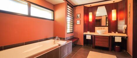 A modern bathroom with a large bathtub, a vanity with a sink, and a mirror.