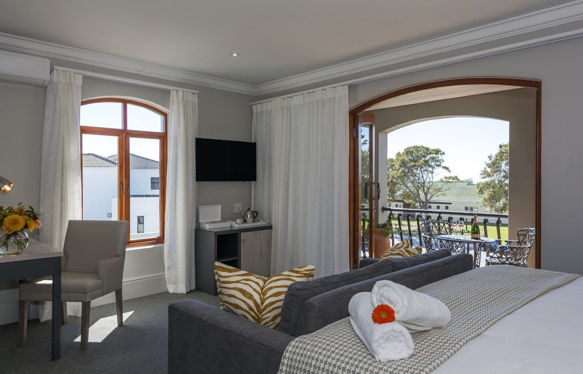 Une chambre d’hôtel avec un balcon, un bureau, une télévision et un lit avec des serviettes.