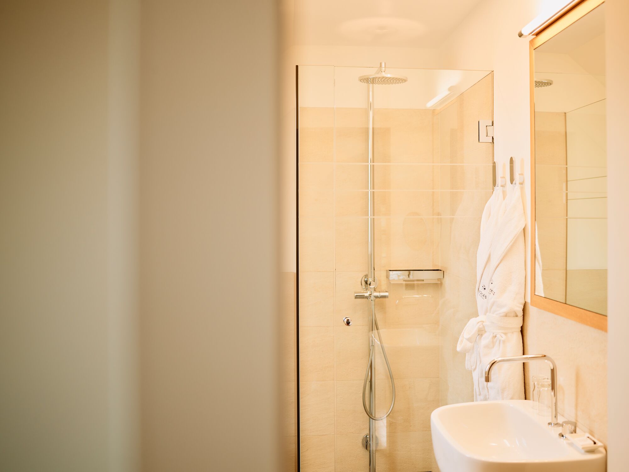 A modern bathroom with a glass-enclosed shower, a white sink, and a mirror.