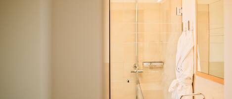 A modern bathroom with a glass-enclosed shower, a white sink, and a mirror.