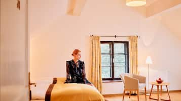 Una habitación con cama, una silla, una mesa y un ventanal con cortinas.
