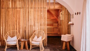 Un sauna en bois avec deux fauteuils en osier, une petite table et une pile de serviettes.