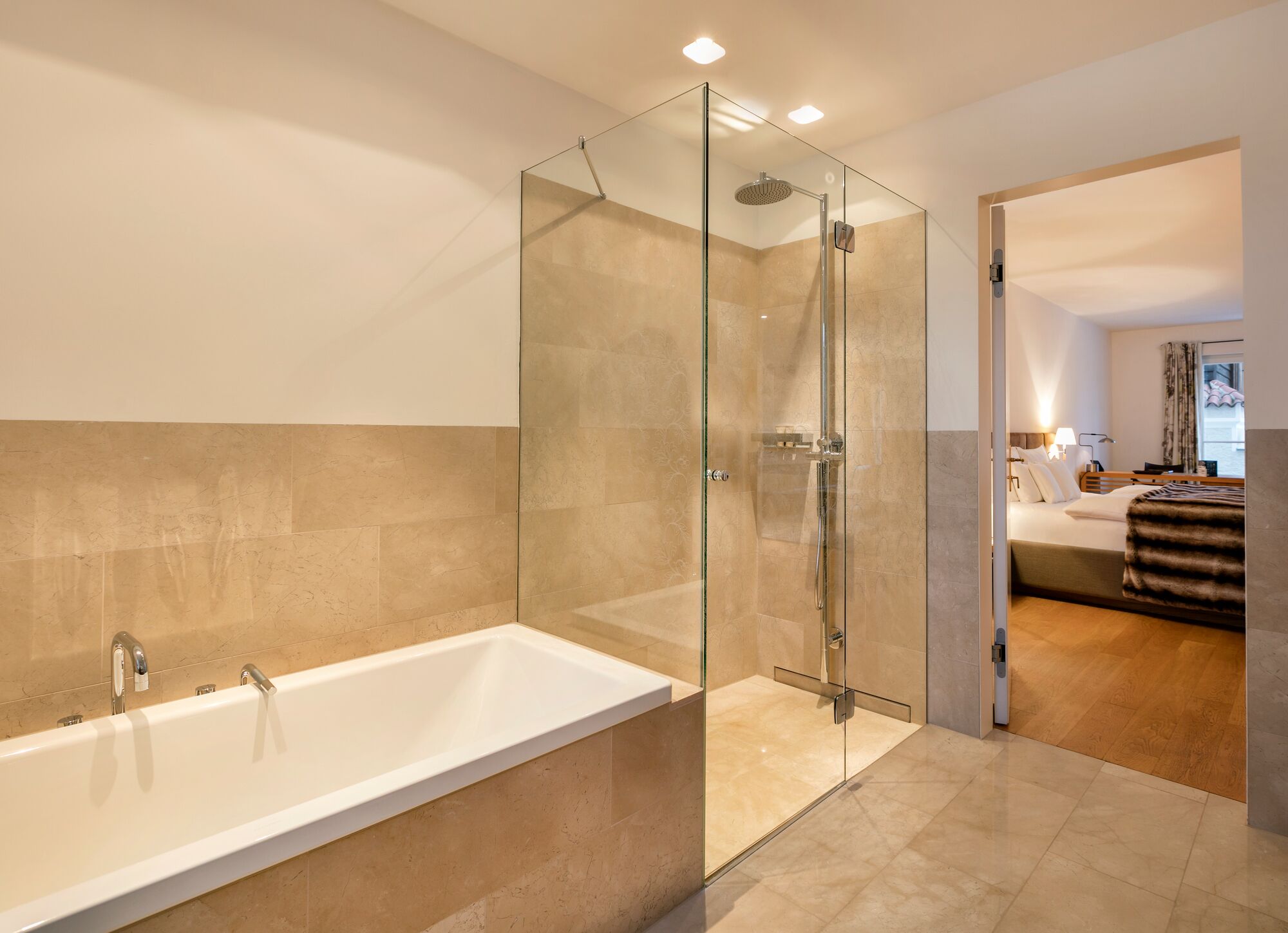 A modern bathroom with a glass-enclosed shower, a white bathtub, and a wooden floor.