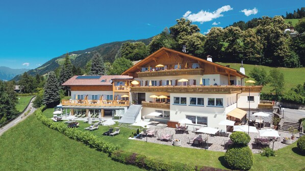 A large, multi-story hotel with outdoor seating areas and a scenic mountain backdrop. - Hotel Mitlechnerhof (Schenna)