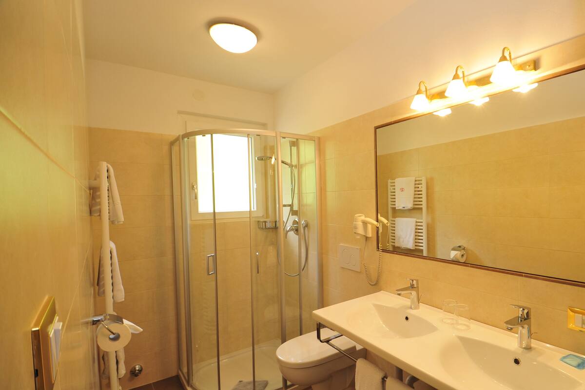 A modern bathroom with a glass shower enclosure, a white toilet, and a vanity with a sink and mirror.