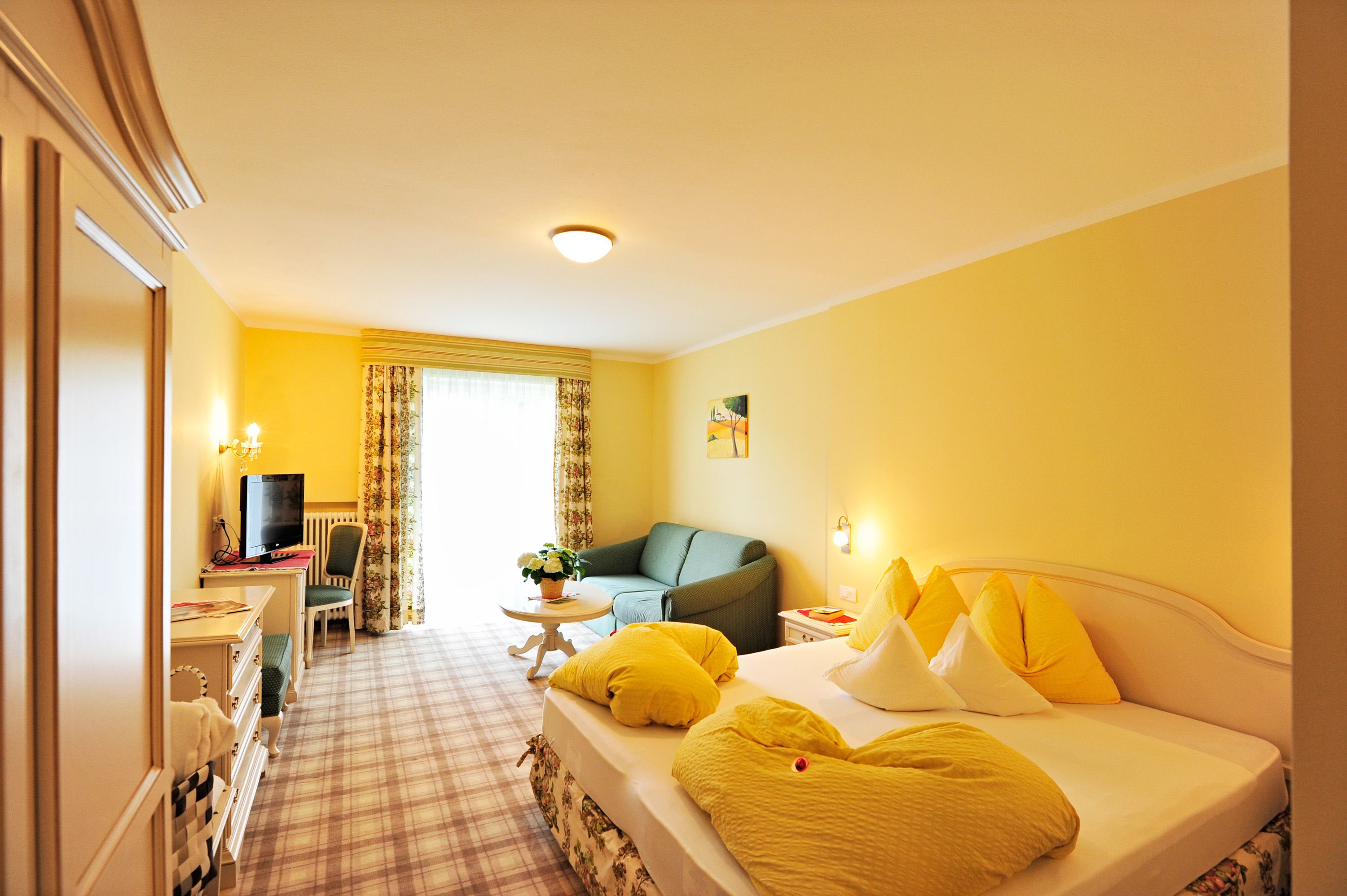 A hotel room with a bed, a desk with a computer, a chair, and a couch.