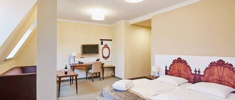 Una habitación de hotel con cama, escritorio, silla, televisor y espejo.