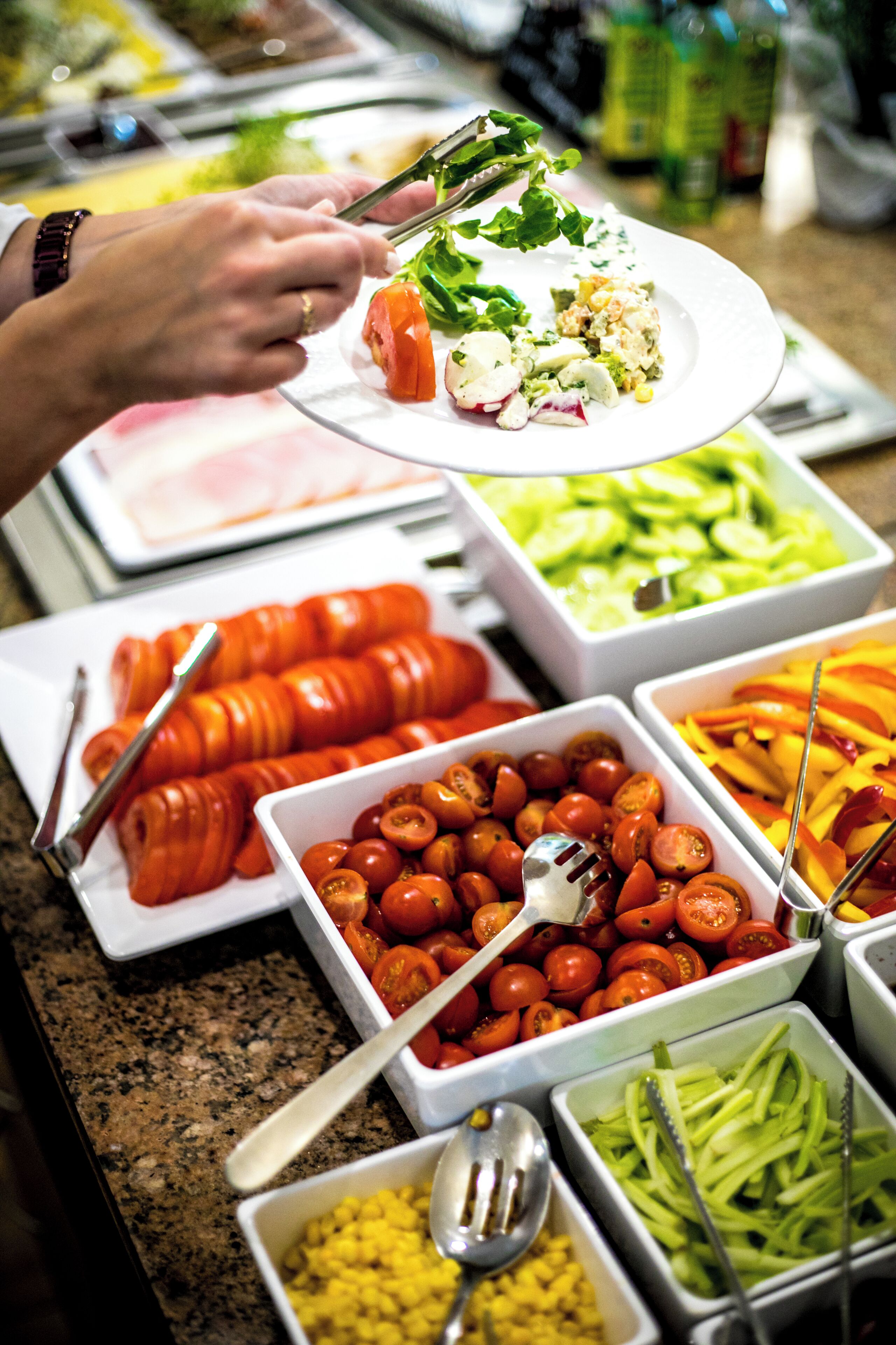 A buffet with various food items including tomatoes, cucumbers, and corn.