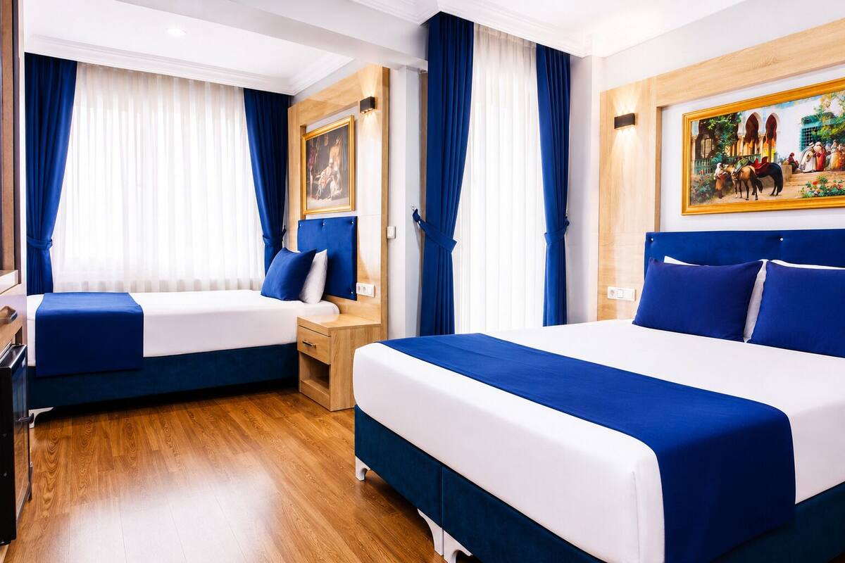 Quarto de hotel com duas camas, piso de madeira e um quadro na parede.