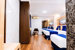 A hotel room with a wooden floor, a desk, a chair, and a bed with blue bedding. - Kadirga Antik Hotel (Istanbul)