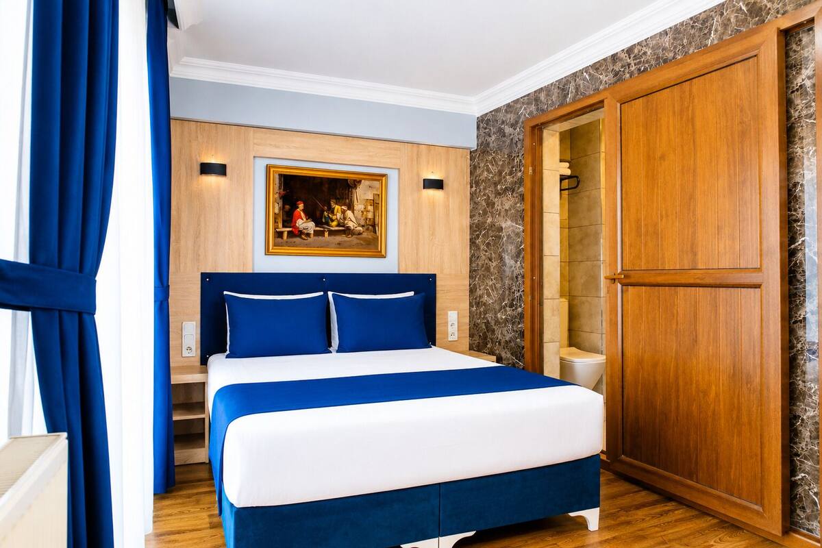 Quarto com cama, guarda-roupa de madeira, quadro na parede e porta de banheiro.