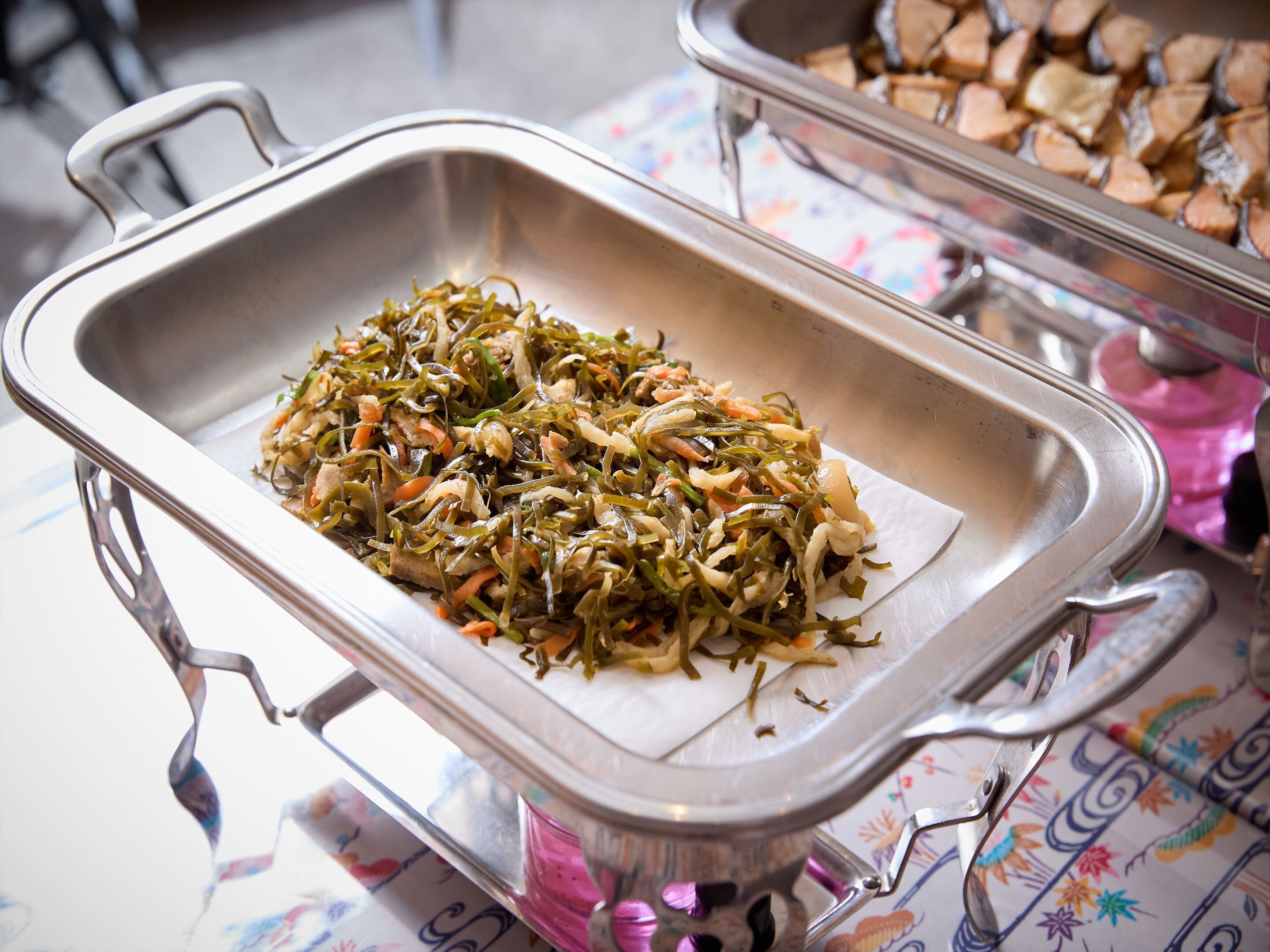 A buffet table with a tray of mixed vegetables and a container of wood chips.