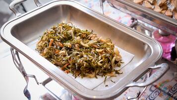 A buffet table with a tray of mixed vegetables and a container of wood chips.
