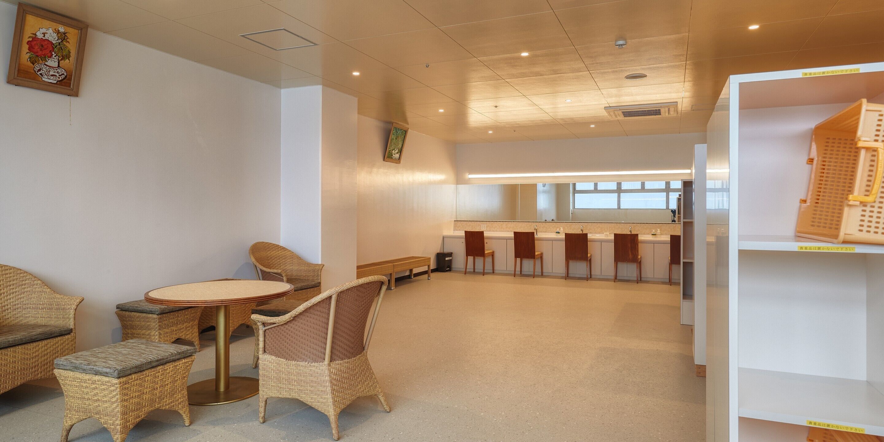 A spacious room with wicker furniture, a round table, and a long bench.