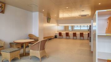 A spacious room with wicker furniture, a round table, and a long bench.