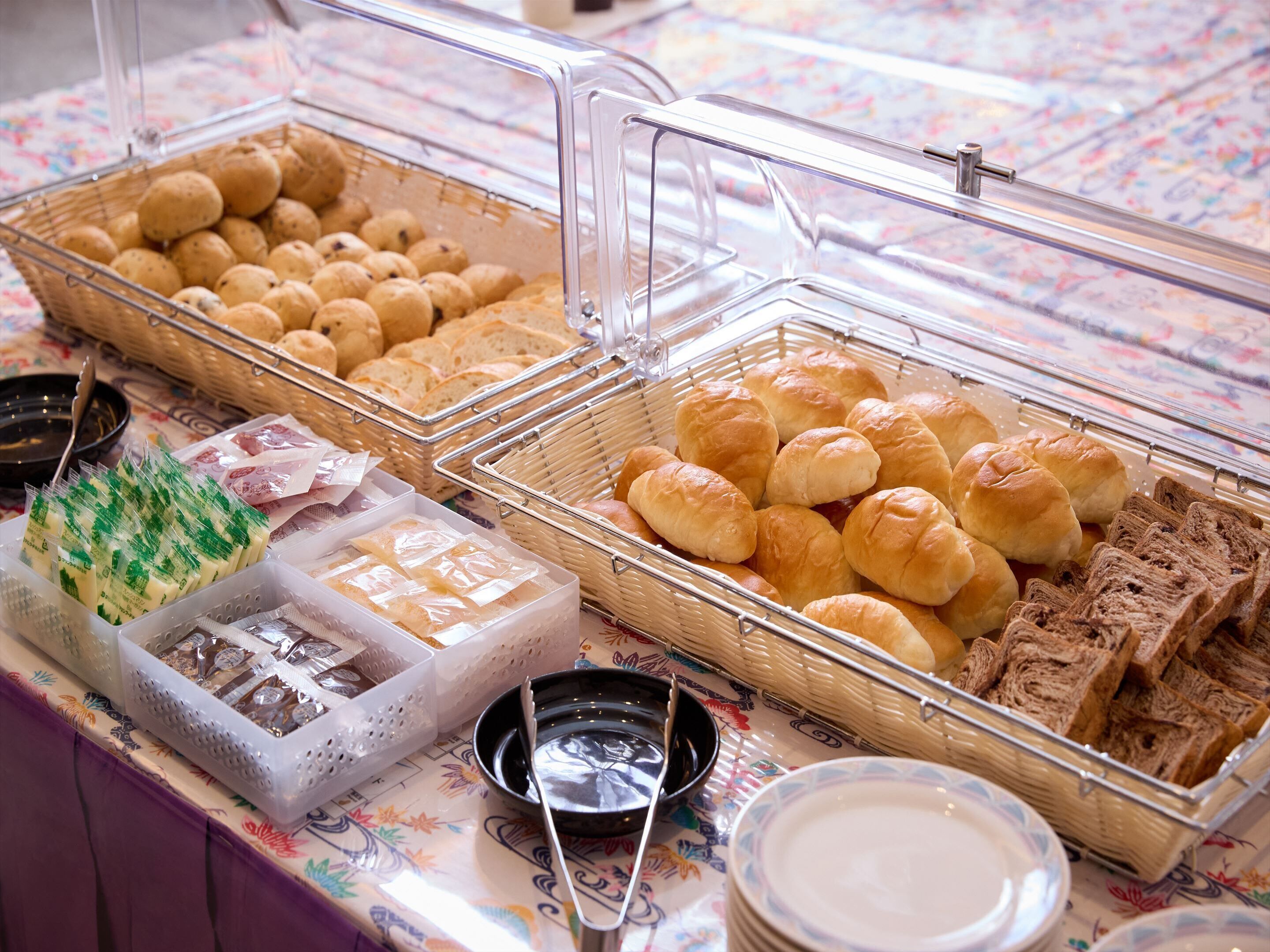 A buffet with various food items including bread rolls, pastries, and sandwiches.