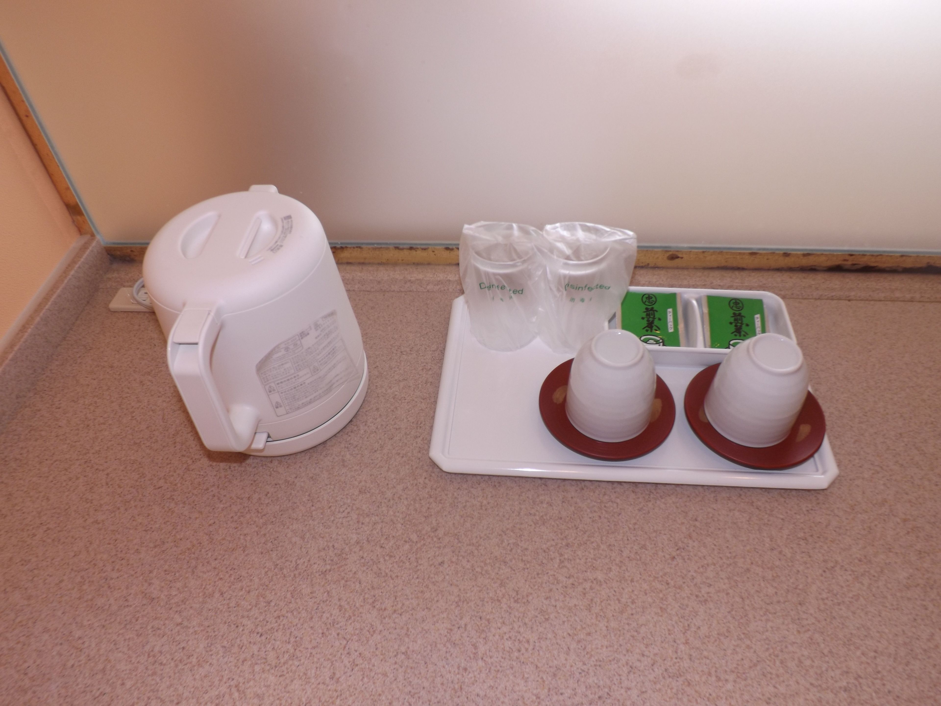 A kitchen area with a white water dispenser, two measuring cups, and a tray with a green label.