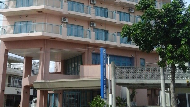 A multi-story hotel with balconies, air conditioning units, and a sign indicating it is a hotel. - Hotel Bell Harmony Ishigakiisland (Ishigaki)