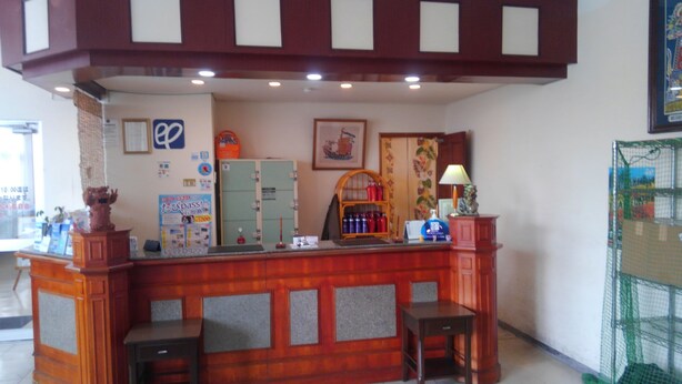 A reception desk with a wooden finish, a framed picture on the wall, and a green cabinet.