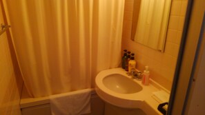 A bathroom with a bathtub, a sink, and toiletries on the counter.