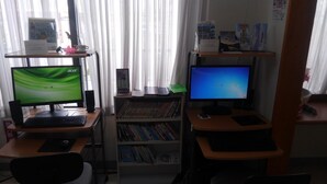 A home office setup with two monitors, a bookshelf, and a desk.
