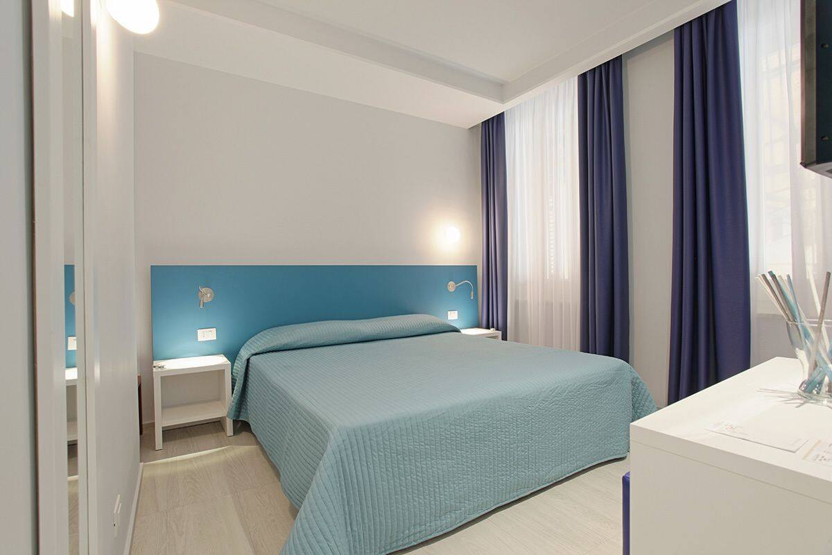 Ein Schlafzimmer mit Bett, Nachttischen, einem Nachtschränkchen und einem Schreibtisch mit Lampe.