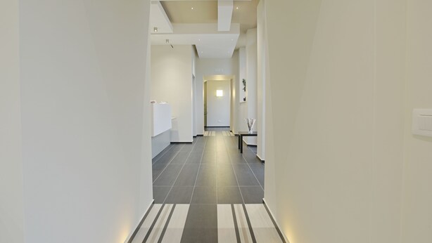 A modern hallway with a striped floor, white walls, and recessed lighting. - Hotel Agrigento Home (Agrigento)