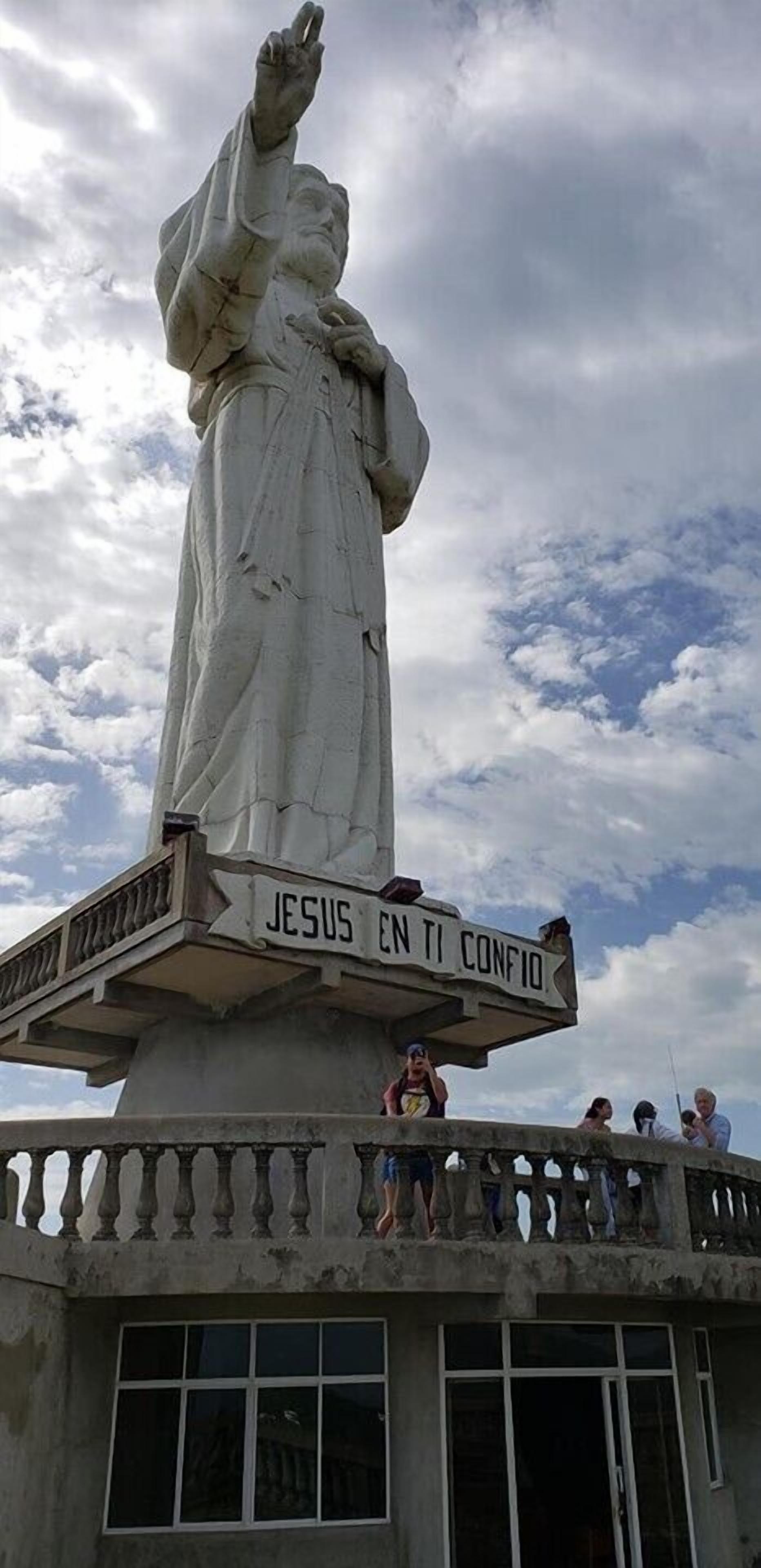Eine Statue von Jesus mit einem Schild, auf dem 'JESUS EN TI CONFIO' steht, auf einem Balkon.