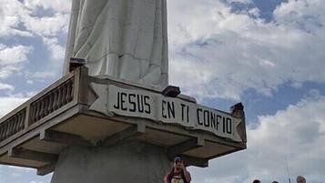 Eine Statue von Jesus mit einem Schild, auf dem 'JESUS EN TI CONFIO' steht, auf einem Balkon.
