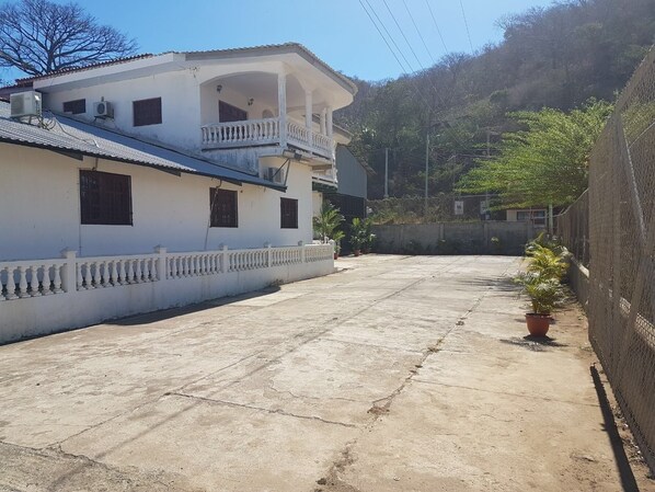 A white building with a balcony, a concrete courtyard, and a fence. - HOTEL & CASINO ATLANTIC CITY de SAN JUAN DEL SUR (San Juan del Sur)