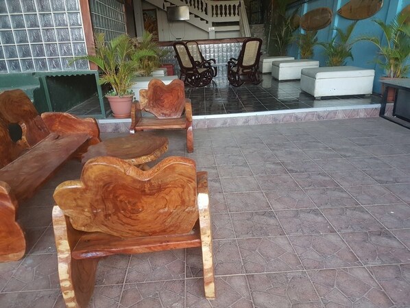 A wooden bench with a unique design, a tiled floor, and a seating area with chairs and a table. - HOTEL & CASINO ATLANTIC CITY de SAN JUAN DEL SUR (San Juan del Sur)