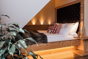 A bedroom with a sloped ceiling, wooden headboard, and a bed with white linens and patterned pillows. - Hotel Restaurant Zum Reussenstein (Boeblingen)