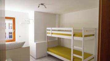 A bunk bed room with white walls and a window.