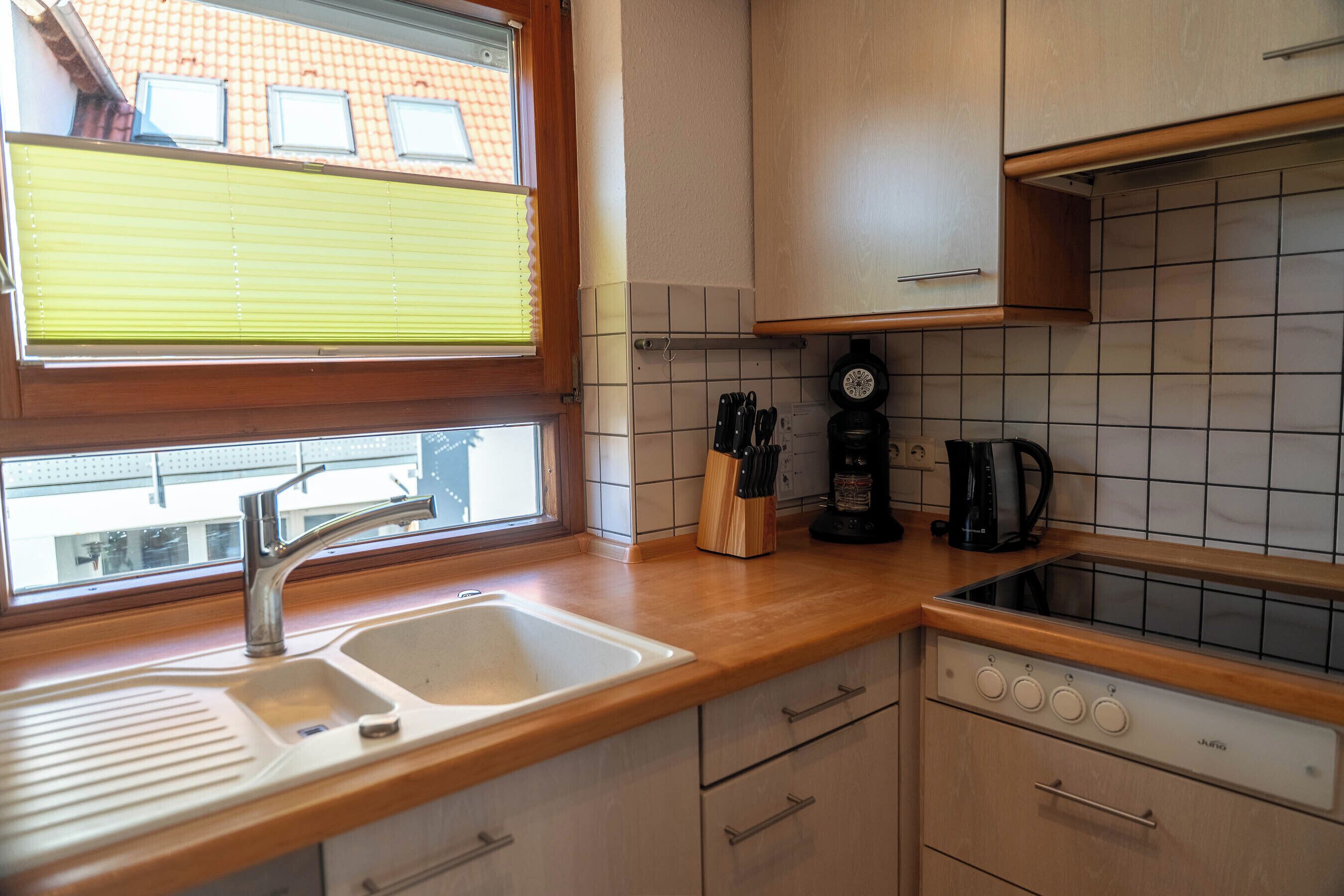 Eine Küche mit Fenster, Spüle, Arbeitsplatte, Schränken und einem Herd.