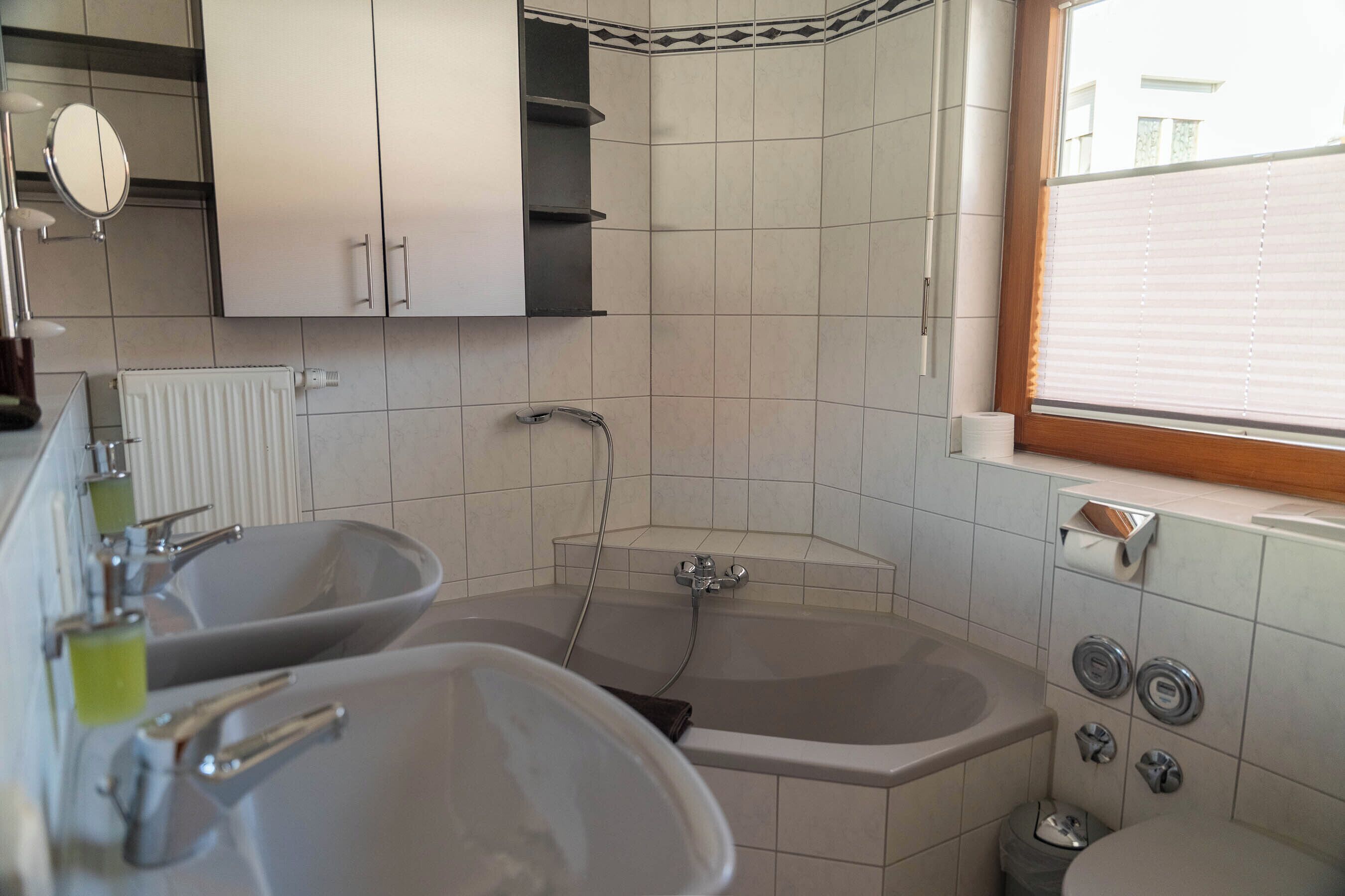 Un baño con dos lavamanos, una bañera y una ventana.