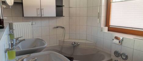 Un baño con dos lavamanos, una bañera y una ventana.