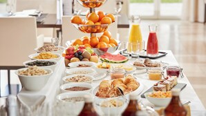 Un bufé de desayuno con diversas frutas, pasteles y bebidas.