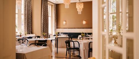 Un restaurante con mesas dispuestas para comer, candelabros y vistas al exterior.